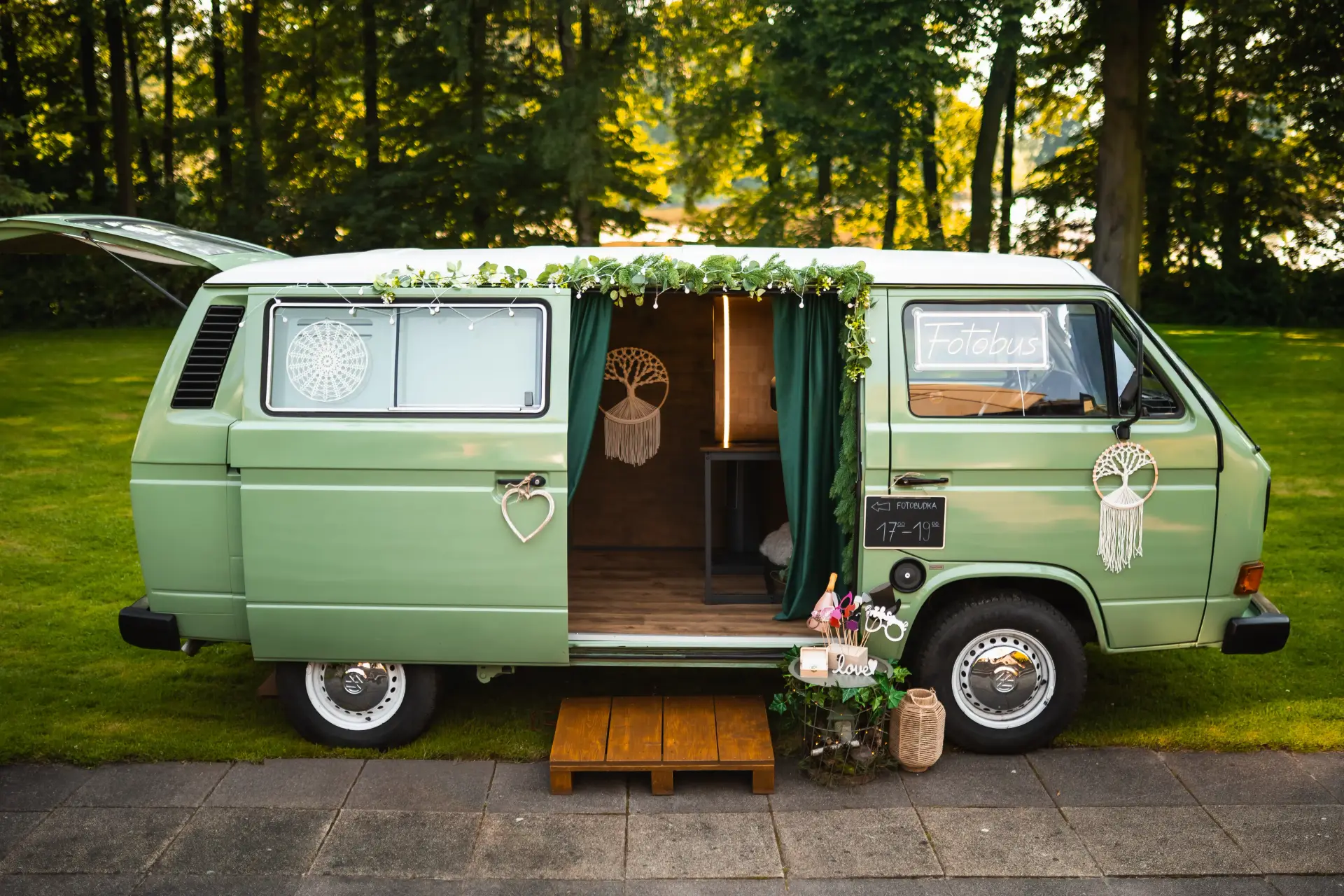 Szałwiowy VW T3 z otwartymi drzwiami na trawie w leśnej scenerii