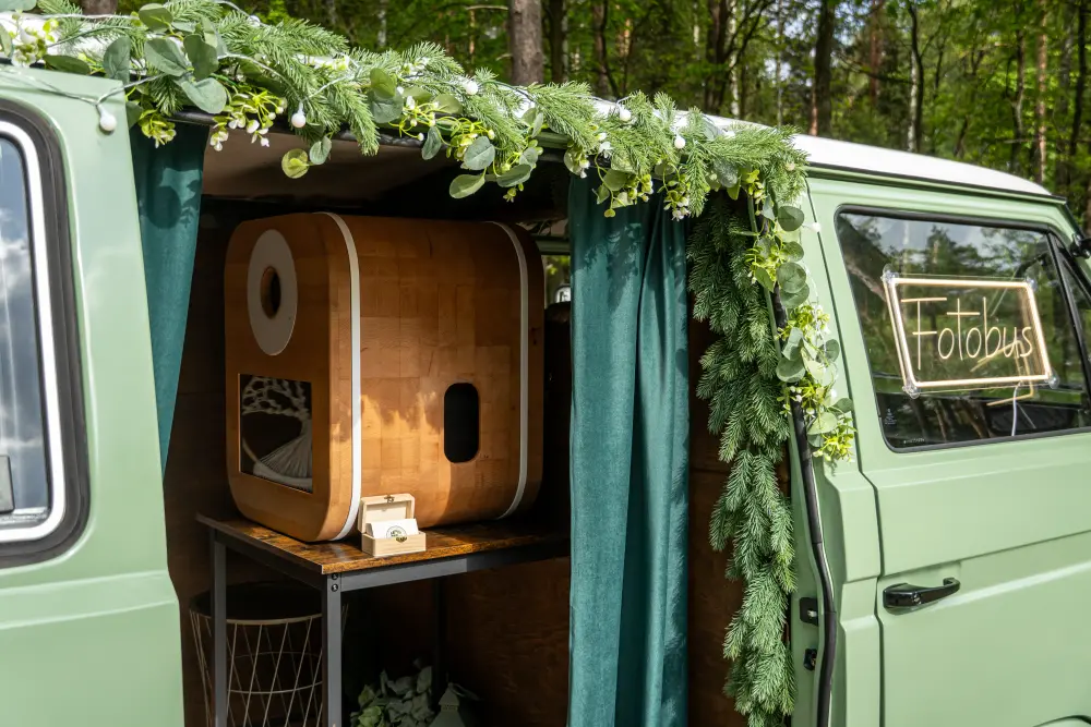 Wejście do fotobudki: drewniana obudowa aparatu, girlanda i podświetlany napis Fotobus